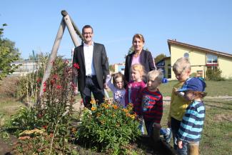 Kundenberater Guido Rammelsberg begutachtet mit Kindern und Kita-Leiterin Anke Gollnick das neu angelegte Blumenbeet. Foto: Pohlmann/Caritas