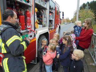 Die Feuerwehrleute erklären den Kindern, was so alles in einem Feuerwehrauto enthalten ist. Foto: Caritas Die Feuerwehrleute erklären den Kindern, was so alles in einem Feuerwehrauto enthalten ist. Foto: Caritas